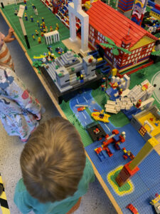 Beispiel für Bausteinewelten - ein Kind steht vor einen aus Klemmbausteinen gebauten Haus