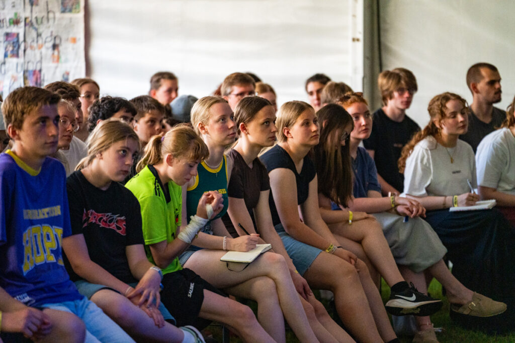 Teilnehmende des J-Camp 2025 sitzen während des Programms im Veranstaltungszelt